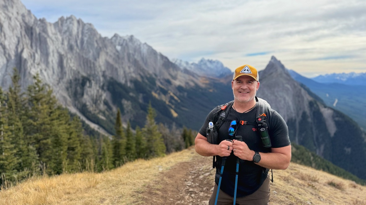 Vince Fowler on a ridge in the Alberta Rockies, pack on, poles in hand